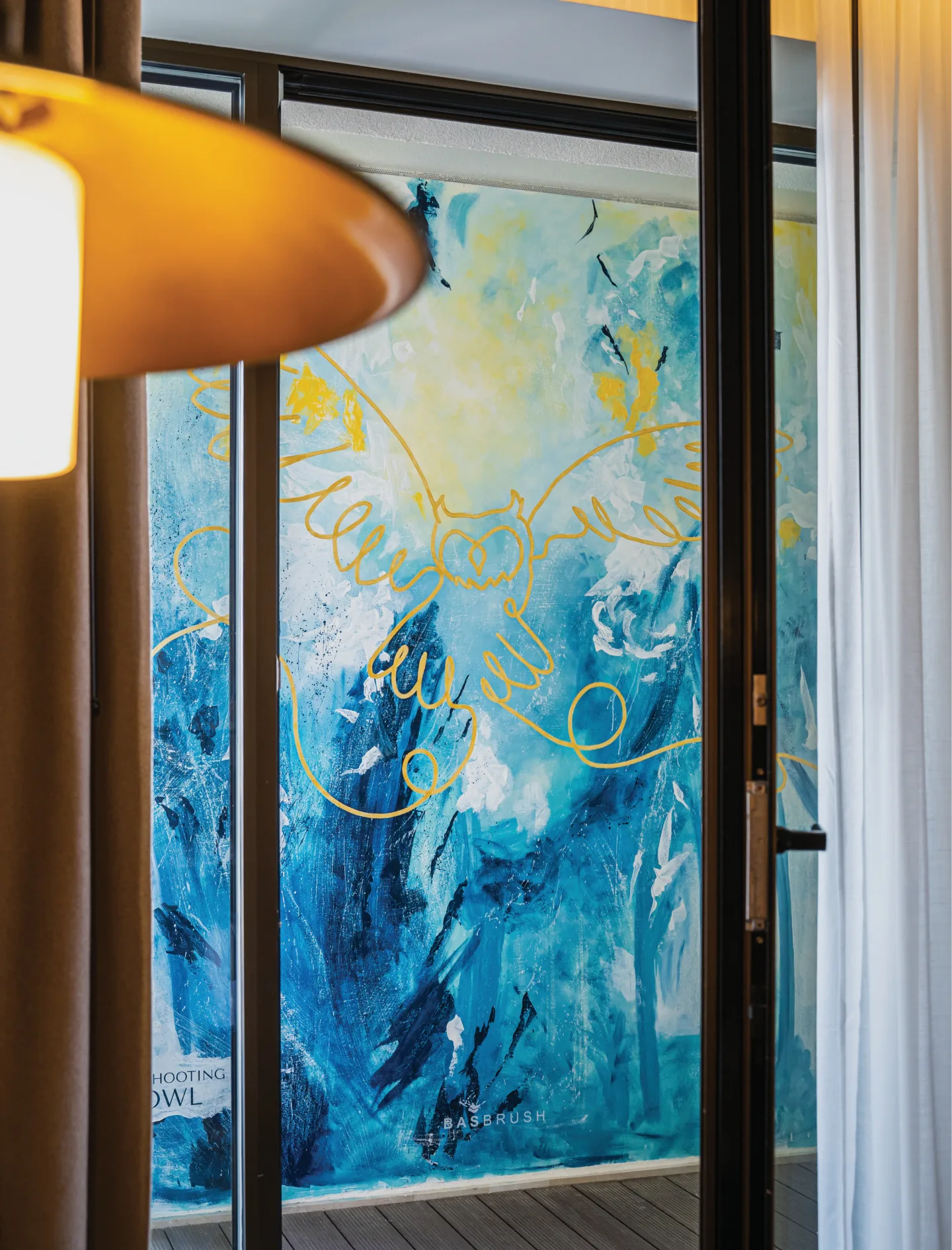 Blue and gold terrace mural viewed through a hotel room doorway.