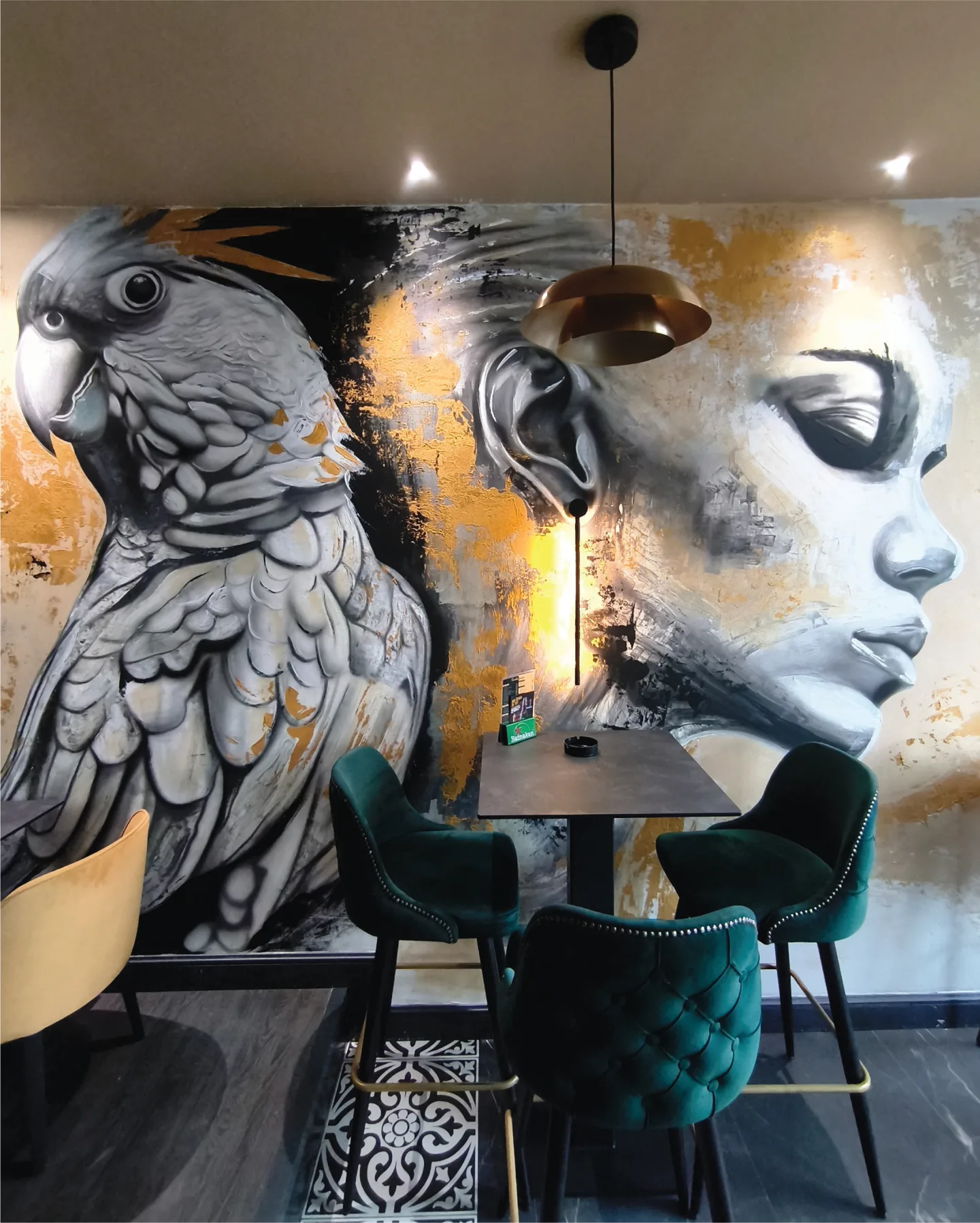 Cockatoo and portrait mural behind café seating.