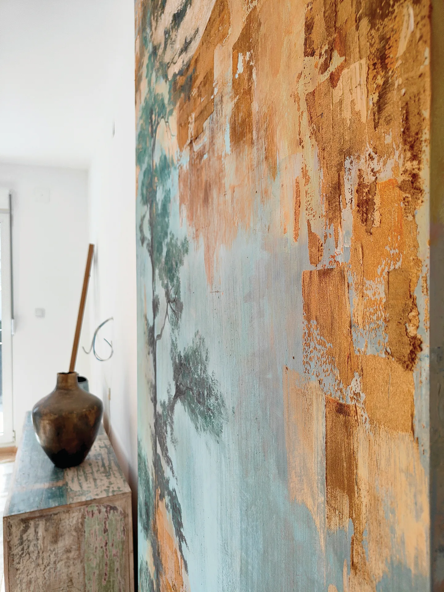 Side view of the textured mural beside a wooden cabinet.