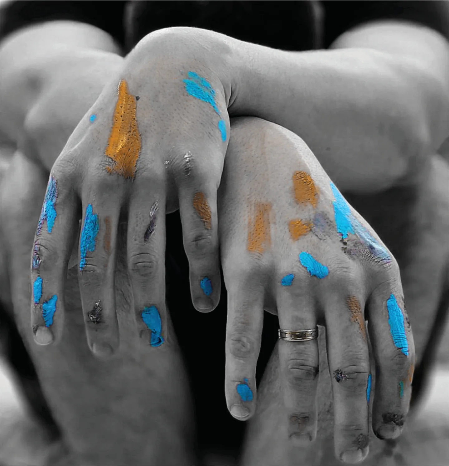 Hands with blue and gold paint on the fingers.