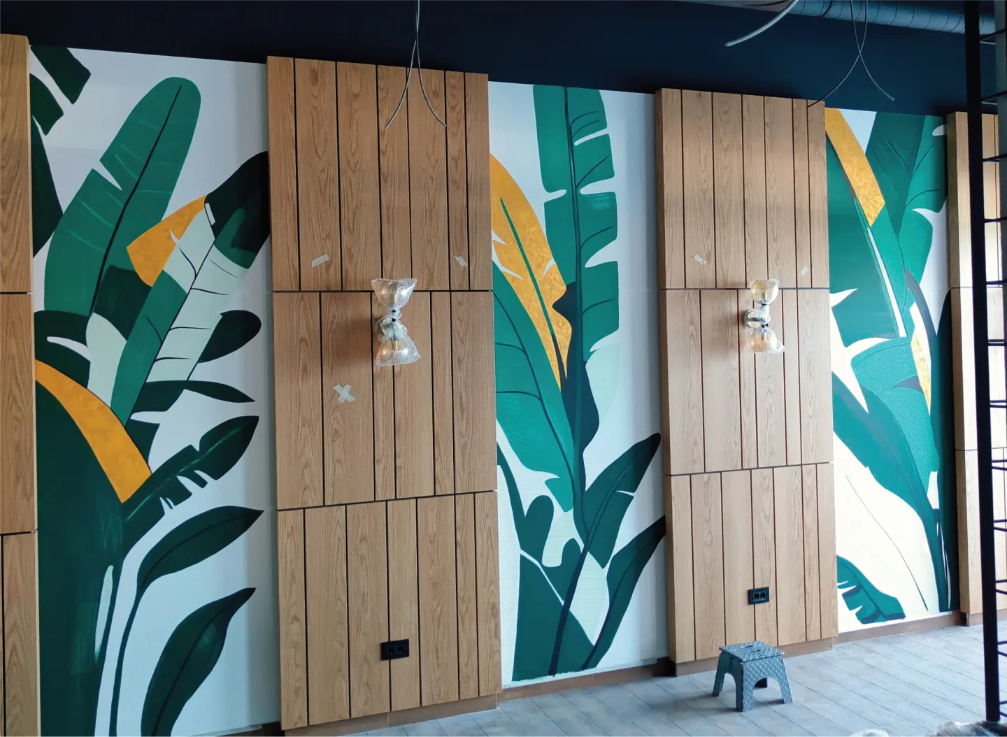 Green botanical mural shapes surrounding a wooden door.