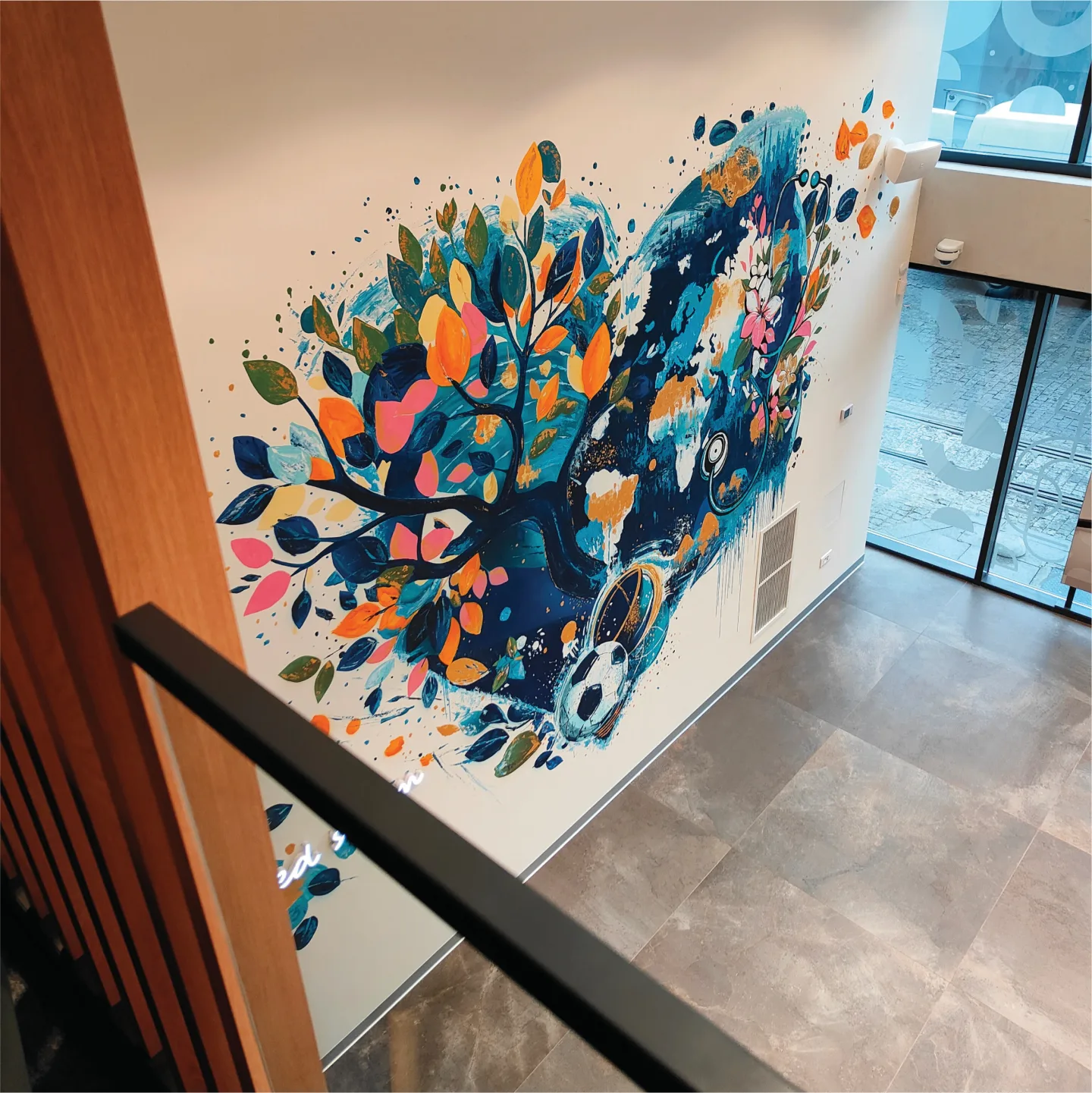 Colourful tree and globe mural viewed from the gallery staircase.