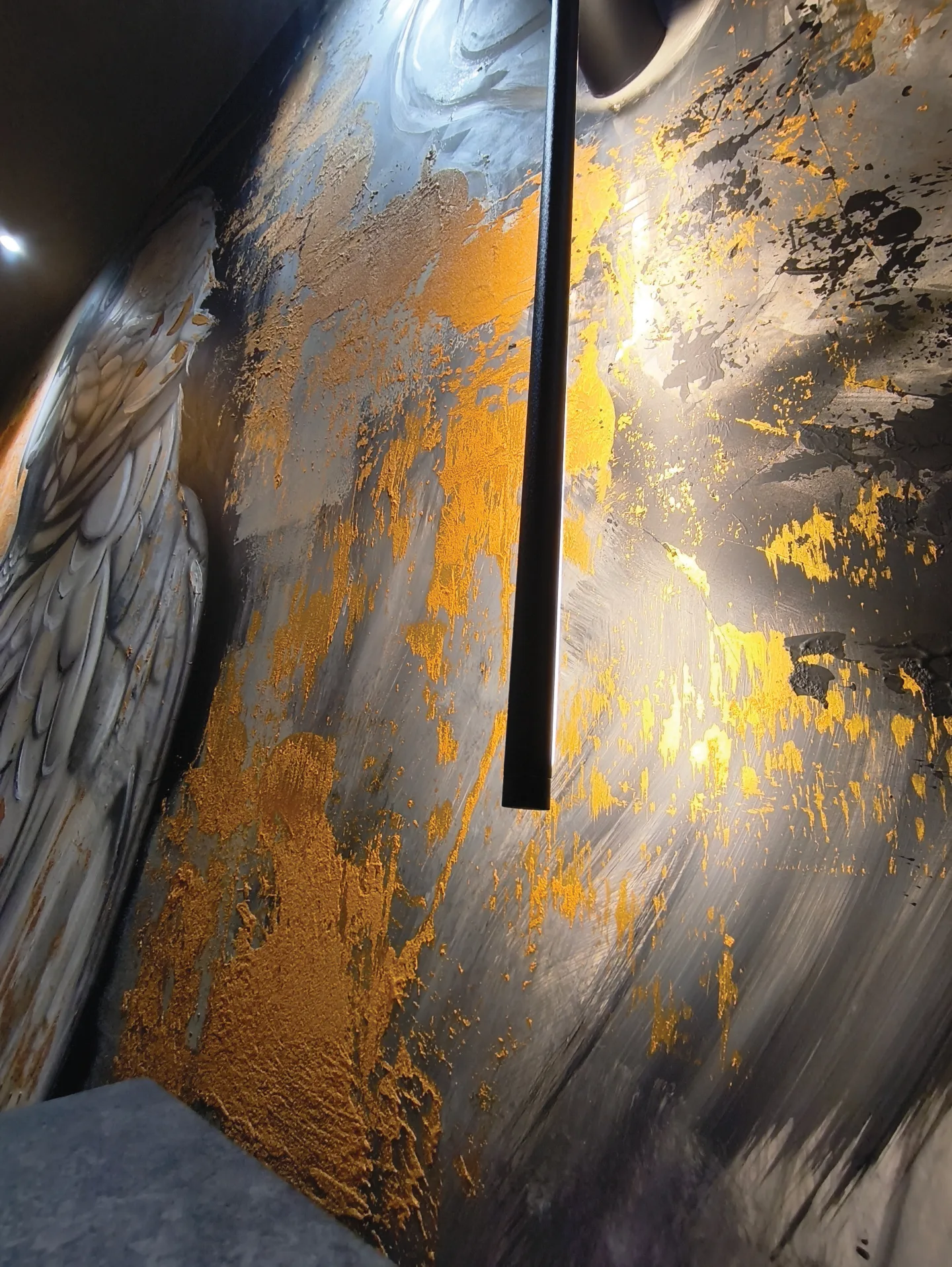Metallic gold and grey mural texture beside a vertical light.